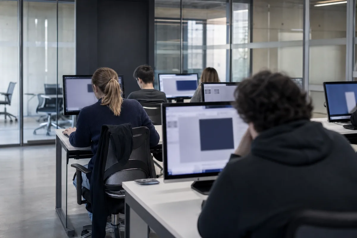 Étudiants en salle de travaux pratiques devant des postes informatiques
